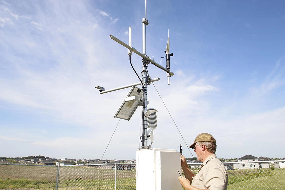 A mesonet technician gazes upon a sensor tower: one might say that this is the technological component to the magic of meteorology.