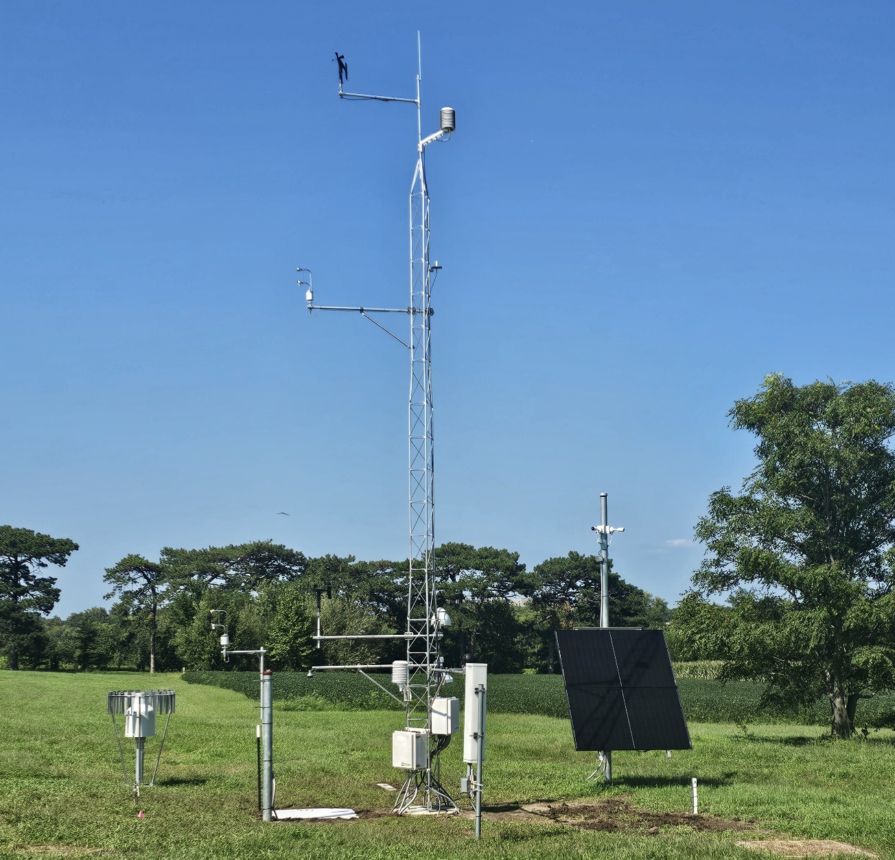 A sensor tower laden with weather measurement devices reaches upward toward a clear Nebraska sky.